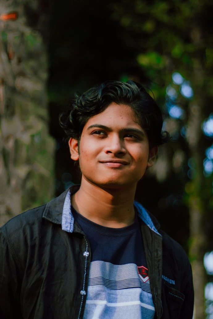 a young man standing in front of a tree